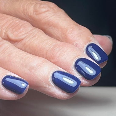 Close-up of a hand with blue nail polish on a neutral background