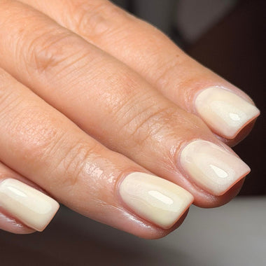 Close-up of a hand with beige nail polish on a blurred background