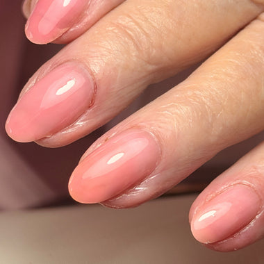 Close-up of a hand with pink nail polish on a neutral background