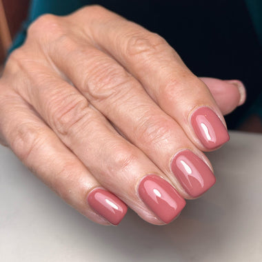 Close-up of a hand with pink nail polish on a neutral background