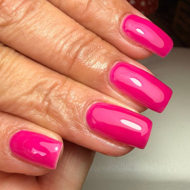 Hand with bright pink nail polish on a neutral background