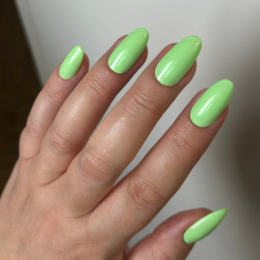 Hand with bright green nail polish on a neutral background