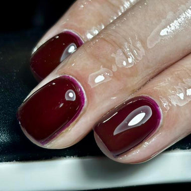 Close-up of a hand with burgundy nail polish on a dark background