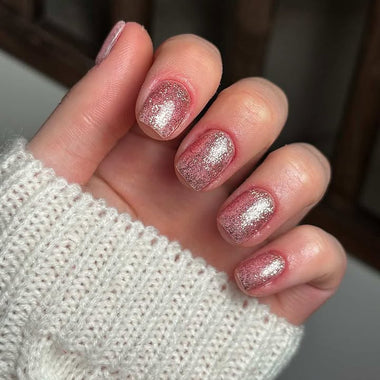 Hand with glittery silver nail polish on a blurred background