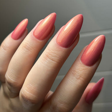 Close-up of a hand with pink nail polish on a neutral background