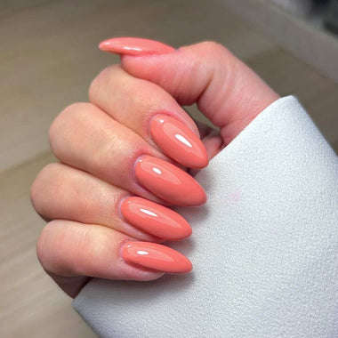 Hand with pink nail polish on a neutral background