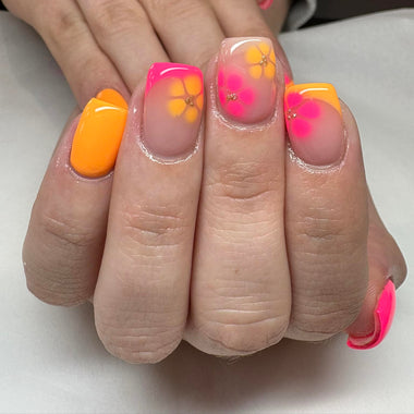 Hand with neon orange and pink floral nail design on a white background