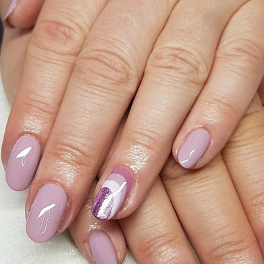 Close-up of hands with pink and purple nail polish on a light background