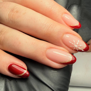 Close-up of a hand with red and gold nail polish on a neutral background
