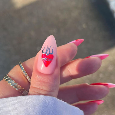 Hand with pink nail polish and a heart design on a blurred background