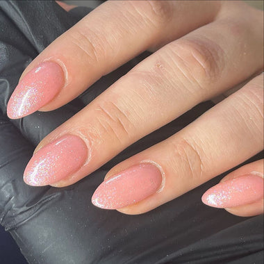 Close-up of a hand with pink glittery nail polish on a black background