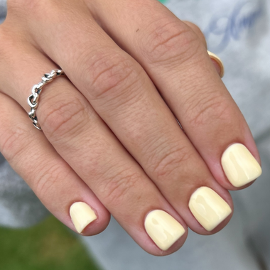 Close-up of a hand with butter yellow nail polish and a silver ring.