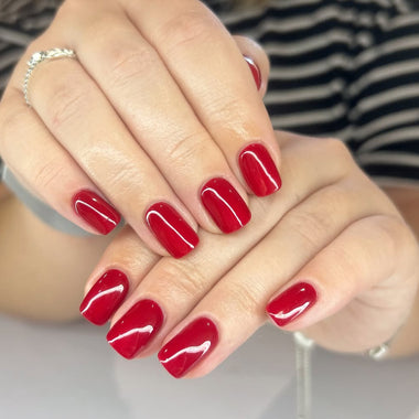 Close-up of hands with red nail polish on a neutral background