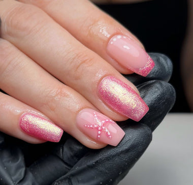 Close-up of a hand with pink and gold glittery nail polish.