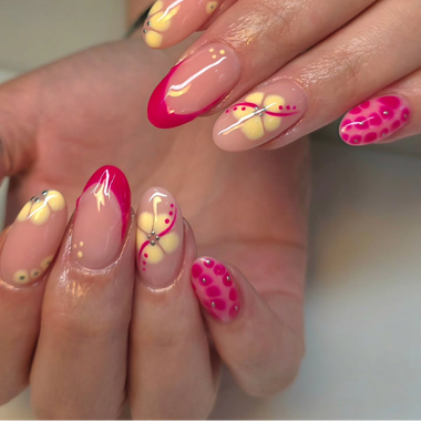 Close-up of a hand with pink and yellow nail art on a neutral background