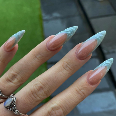 Hand with long, decorative nails featuring a marble pattern.