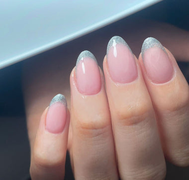 Close-up of a hand with pink nails and silver glitter tips.