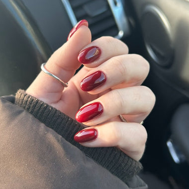 Hand with red nail polish holding a small object inside a vehicle.