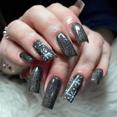 Close-up of a hand with dark glittery nail polish on a neutral background