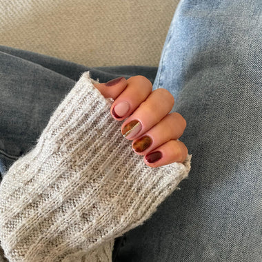 Close-up of a hand wearing a beige knit sleeve with a blurred background