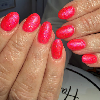 Close-up of hands with bright pink nail polish on a blurred background