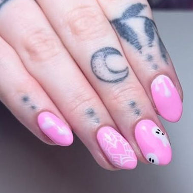 Close-up of hands with pink nails and tattoos on a neutral background