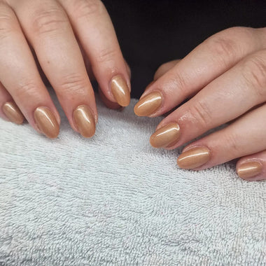 Close-up of hands with beige nail polish on a textured gray surface