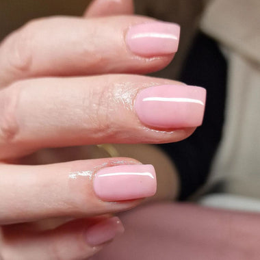 Close-up of a hand with pink nail polish on a blurred background