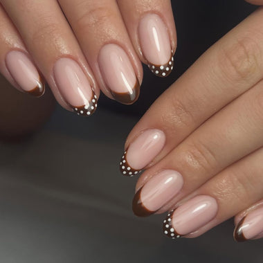Close-up of hands with pink and brown nail polish on a dark background