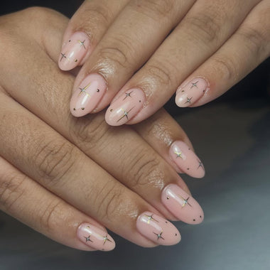 Close-up of hands with pink nail polish and star designs on a dark background