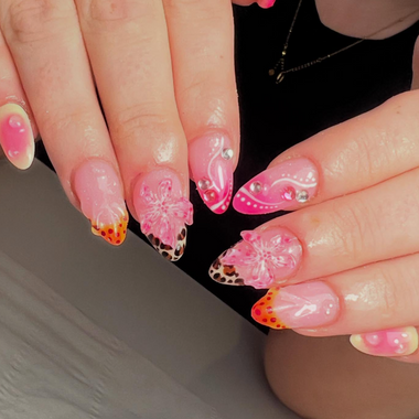 Close-up of hands with pink and orange nail art on a neutral background