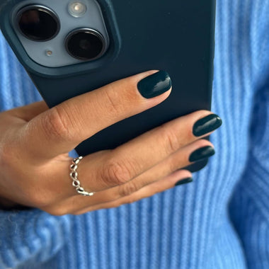 Hand holding a phone with dark blue case against a blue textured background