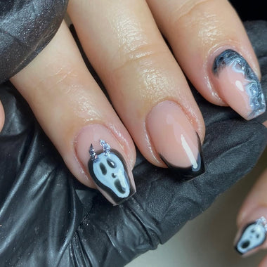 Nail art with ghost designs on a black glove background