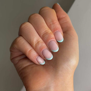 Close-up of a hand with pastel nail polish on a neutral background