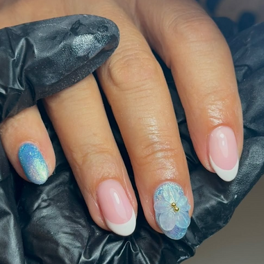 Hand with blue glittery nail design on a black background