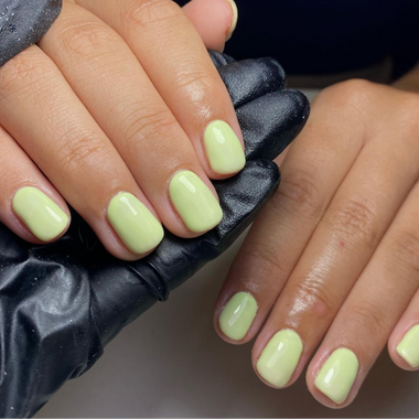 Close-up of hands with light green nail polish wearing black gloves.