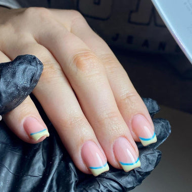 Hand with painted nails wearing a black glove, possibly during a manicure.
