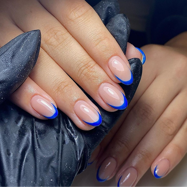 Close-up of hands with blue and beige nail design on a dark background
