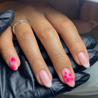 Hand with pink and white nail polish wearing a black glove