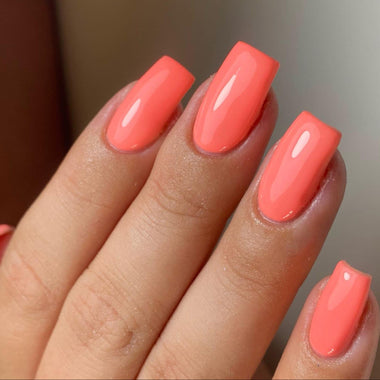 Close-up of a hand with pink nail polish on a blurred background