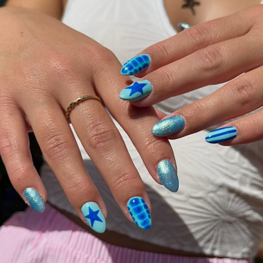 Close-up of hands with blue nail designs, including stars and stripes.