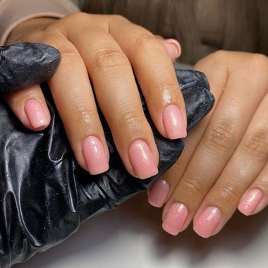 Close-up of hands with pink nail polish holding a black scrunchie.