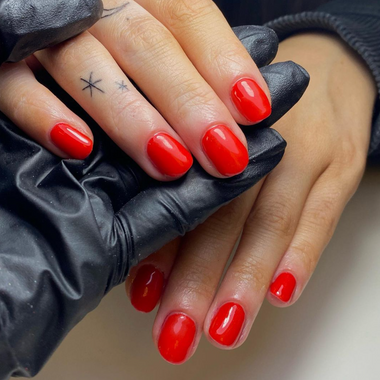 Close-up of hands with red nail polish wearing black gloves.