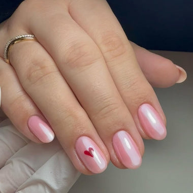 Hand with pink nail polish and a heart design on a neutral background