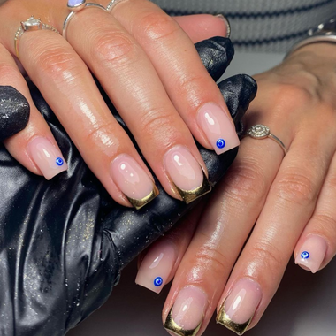 Close-up of hands with manicured nails featuring gold and blue accents.