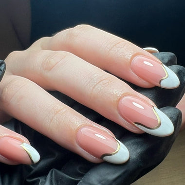 Hand with pink and white nails with gold accents on a dark background