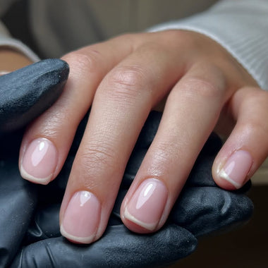 Hand with black glove holding a small object, blurred background