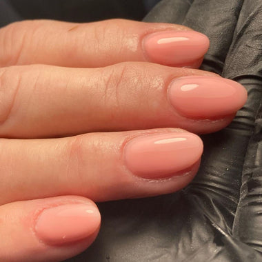 Close-up of a hand with pink nail polish on a black background