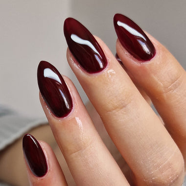 Close-up of a hand with dark red nail polish on a neutral background