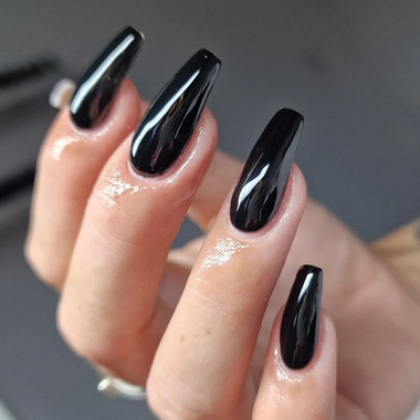 Close-up of a hand with black nail polish on a neutral background